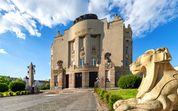Historisches Gebäude mit Skulpturen und blauem Himmel im Hintergrund.
