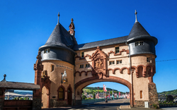 Historisches Stadttor mit Türmen und Durchgang bei klarem Himmel.
