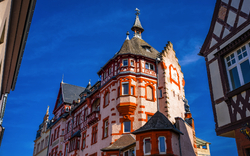 Historisches Gebäude mit Fachwerk und Türmen unter blauem Himmel.
