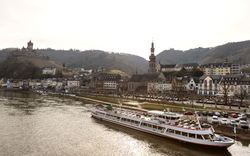 Flusslandschaft mit Ausflugsschiff, Altstadt und Burgruine im Hintergrund.