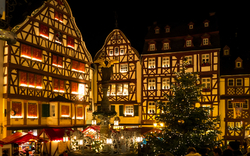 Weihnachtsmarkt bei Nacht mit Fachwerkhäusern und Weihnachtsbaum.