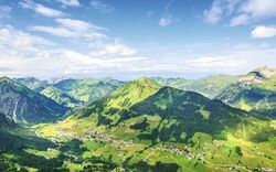 Landschaft mit grünen Bergen und blauem Himmel in den Alpen.
