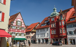 Historischer Marktplatz mit Fachwerkhäusern und blauem Himmel.