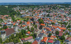 Luftaufnahme einer Stadt mit vielen bunten Dächern und umgebender Landschaft.