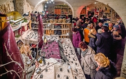 Menschen besuchen einen Handwerksmarkt in einem Gewölbekeller.