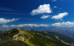 Berglandschaft mit grünen Hügeln und blauem Himmel.