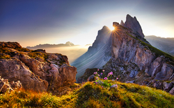 Berglandschaft mit Sonnenstrahlen hinter einem Gipfel bei Sonnenuntergang.