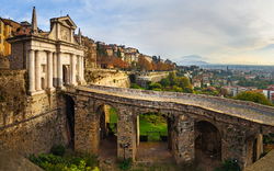 Stadtmauer mit Tor und Panoramablick auf historische Stadt und Landschaft.