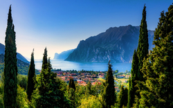 Blick auf eine Stadt am Gardasee, umgeben von Zypressen und Bergen.