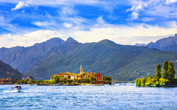 Insel mit Gebäuden auf einem See, Berge im Hintergrund.
