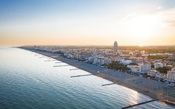 Küstenpanorama mit Strandpromenade und Hochhäusern bei Sonnenuntergang.