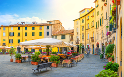 Italienischer Platz mit Cafés und gelben Gebäuden bei sonnigem Wetter.