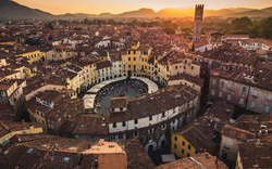 Luftaufnahme einer Piazza in italienischer Stadt bei Sonnenuntergang mit umliegenden Dächern.