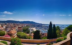 Panorama einer Küstenstadt mit Hafen und umliegenden Hügeln unter klarem Himmel.