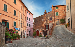 Gepflasterte Gasse mit bunten Häusern in einer ruhigen italienischen Stadt.